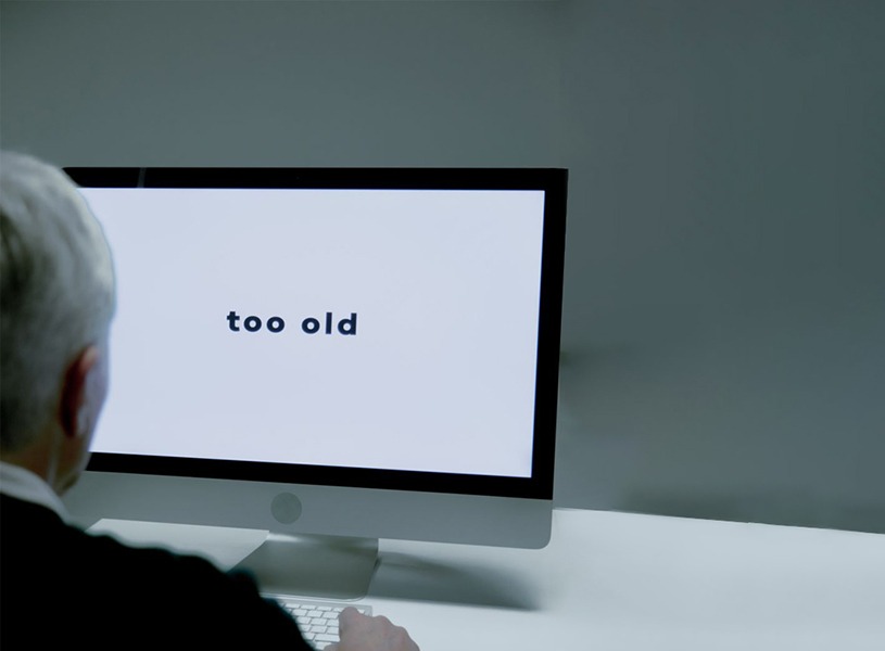 Alzheimer: stigma legato alla demenza - persona anziana di fronte al computer, "too old" scritto sullo schermo.
